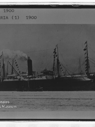 Dampfschiff mit Schornstein und beflaggten Masten; oben sichtbarer Text: ITHAKA 1900, schwarz-weiß.