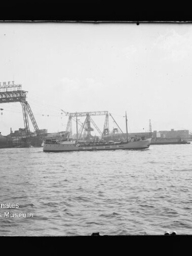 Kleines Handelsschiff im Hafen vor großen Werftkränen mit dem Schriftzug Stülckenwerft
