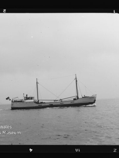Kleiner Frachter mit zwei Masten auf ruhiger See unter bedecktem Himmel; Wasserzeichen Internationales Maritimes Museum Hamburg