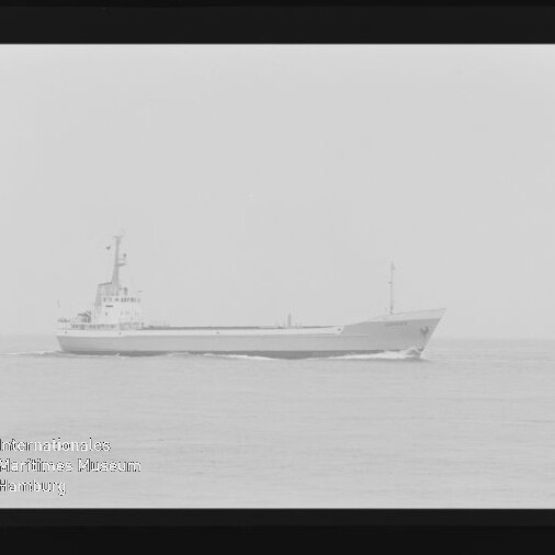 Schwarzweißfoto eines Frachtschiffs auf ruhiger See mit sichtbarem Filmrand und Museumswasserzeichen.