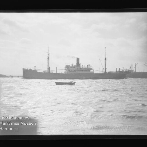Graustufenaufnahme eines Frachtschiffs am Horizont mit kleinem Ruderboot im Vordergrund und Wasserzeichen 