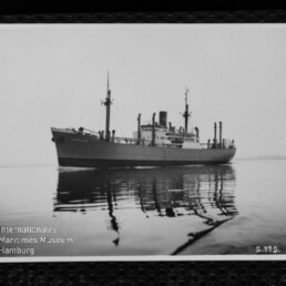 Frachtschiff mit Schornstein und Masten auf ruhigem Wasser mit klarer Spiegelung, Text Maritimes Museum Hamburg sichtbar.
