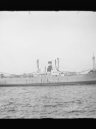 Seitliche Ansicht eines historischen Frachtschiffs mit Schornstein und Ladebäumen auf ruhigem Wasser, Museumslogo unten links.