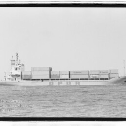 Frachtschiff mit gestapelten Containern und Schriftzug OPDR auf dem Rumpf, auf ruhiger See; Schwarzweißaufnahme mit Museumswasserzeichen.