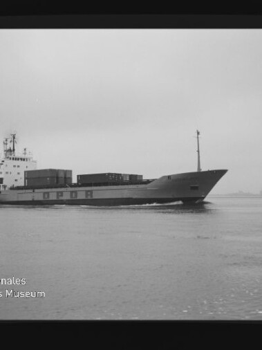 Schwarzweiß-Foto eines Frachtschiffs mit Containerladungen auf ruhiger See und Museumslogo links unten.