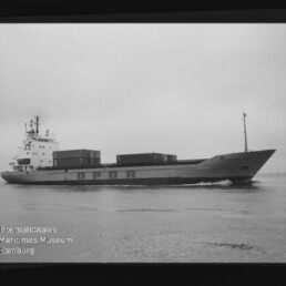 Schwarzweiß-Seitenansicht eines Frachters mit Containerladung und sichtbarem Logo Internationales Maritimes Museum Hamburg