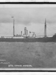 Schwarzweiß-Foto eines historischen Dampfschiffs mit Schornstein und Masten auf ruhiger See, Text 