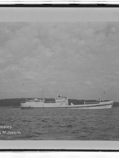 Frachtschiff auf ruhiger See vor bewölktem Himmel, links unten Wasserzeichen Internationales Maritimes Museum Hamburg