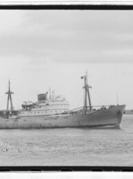 Schwarzweißaufnahme eines Frachtschiffs mit zwei Masten und Schornstein auf ruhiger See.