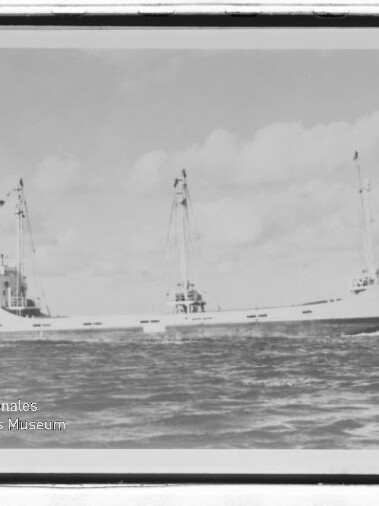 Schwarzweißfoto eines Frachtschiffs mit zwei Masten auf ruhiger See, Museumswasserzeichen unten links.
