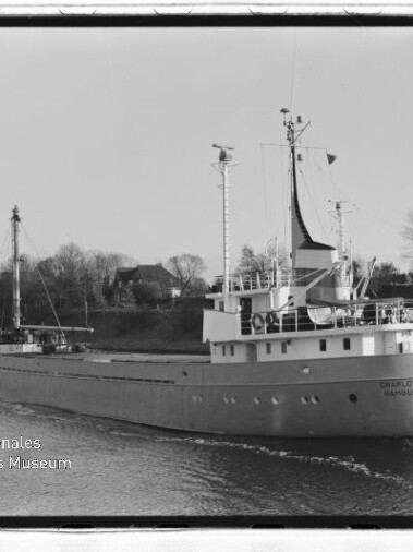 Schwarzweißaufnahme eines Frachtschiffs mit Masten auf einem Fluss; Wasserzeichen Internationales Maritimes Museum Hamburg