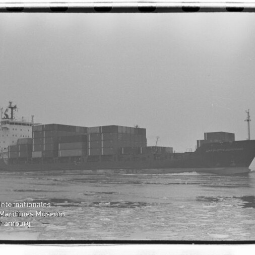 Containerschiff mit gestapelten Containern auf ruhiger See; schwarzweißes Foto mit Wasserzeichen des Maritimen Museums.