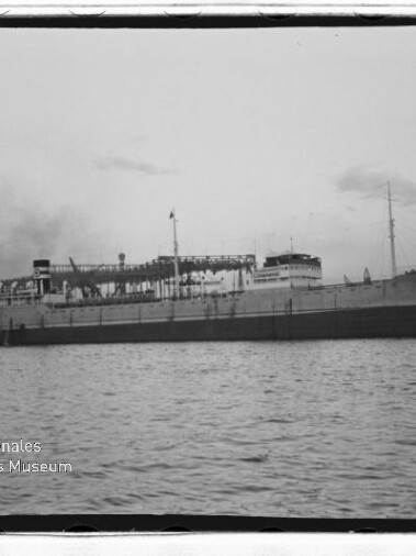 Schwarzweißaufnahme eines großen Dampfschiffs längsseits vor Hafen, ruhige See; Wasserzeichen Internationales Maritimes Museum Hamburg.