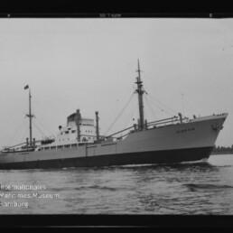 Frachtschiff Alexine in Seitenansicht auf ruhigem Wasser, klare Silhouette mit Aufbauten und Masten sichtbar