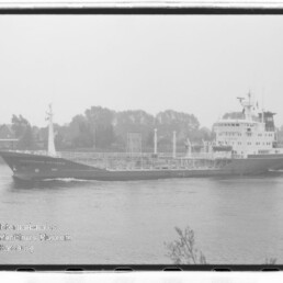 Frachtschiff mit Deckspipelines und Aufbauten fährt auf ruhigem Fluss, Wasserzeichen des Maritimen Museums Hamburg.