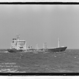 Schwarzweißaufnahme eines Tankschiffs auf leicht bewegter See, mit Rahmen und Schriftzug 