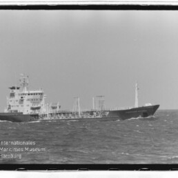 Tankterschiff mit Aufbauten achtern fährt auf offener See, im Bild unten links Museumslogo