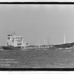 Mittleres Tankschiff mit Aufbau achtern und sichtbaren Rohrleitungen auf hoher See, Wasserzeichen des Museums.