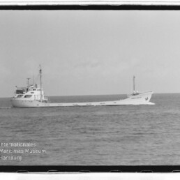 Langes Frachtschiff mit achterlicher Brücke auf ruhiger See, Schwarzweiß; Logo und Schriftzug 