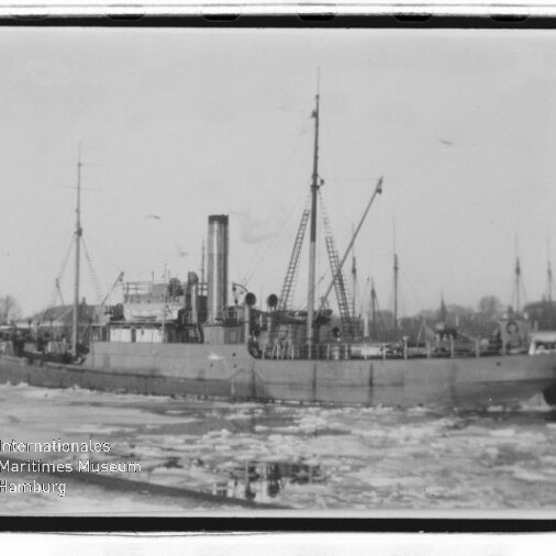Historisches Dampfschiff mit hohem Schornstein und Kränen liegt in eisbedecktem Hafenbecken, Museumslogo links unten.