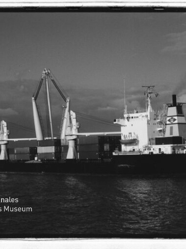 SW-Foto eines Frachtschiffs mit Ladekränen und Containern auf See; links unten Wasserzeichen Maritimes Museum Hamburg