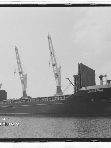Frachtschiff CHRISTINA liegt am Kai neben großen Hafenkränen; Schwarzweißaufnahme mit ruhigem Wasser.