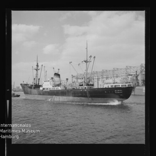 Frachtschiff mit Ladekranen vor Industriehafen, Museumswasserzeichen links unten.