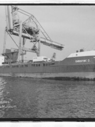 Frachtschiff CHRISTINE C. am Industriequai neben großem Hafenkran, im Vordergrund Wasser.