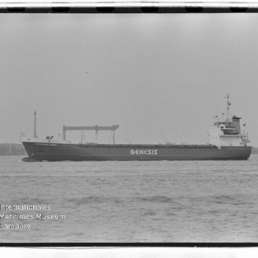 Frachtschiff mit Aufschrift GENESIS fährt auf ruhiger See vor einem Hafen, schwarz-weiß, Museumslogo unten links.