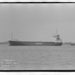 Großes Frachtschiff auf ruhigem Wasser, unscharf, mit Wasserzeichen Internationales Maritimes Museum Hamburg unten links.