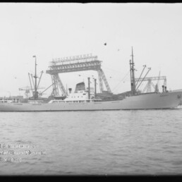 Frachtschiff Alaska am Hafen vor großen Ladekränen und Kaimauern, ruhige See