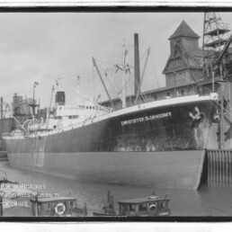 Großes Frachtschiff CHRISTOFFER OLDENDORFF am Industriehafen mit Lagergebäuden und Kränen im Hintergrund.
