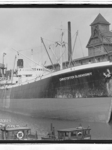 Großes Frachtschiff CHRISTOFFER OLDENDORFF am Industriehafen mit Lagergebäuden und Kränen im Hintergrund.