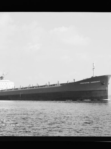 Langes Massengutfrachtschiff in Seitenansicht fährt ruhig über das Meer, Schiffsnamen auf dem Bug sichtbar.