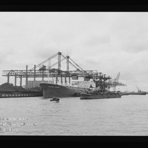 Frachtschiff am Industriehafen unter großen Ladekränen, Schuten im Wasser; Wasserzeichen: Maritimes Museum Hamburg