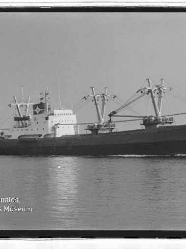 Schwarzweiß-Archivfoto eines Frachtschiffs mit Ladekränen und Deckshaus auf See; Logo Maritimes Museum Hamburg.