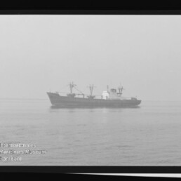 Schwarzweißfoto eines Frachtschiffs mit Ladekränen auf ruhiger See, sichtbarer Filmrand mit KODAK-Schriftzug und Museumslogo.