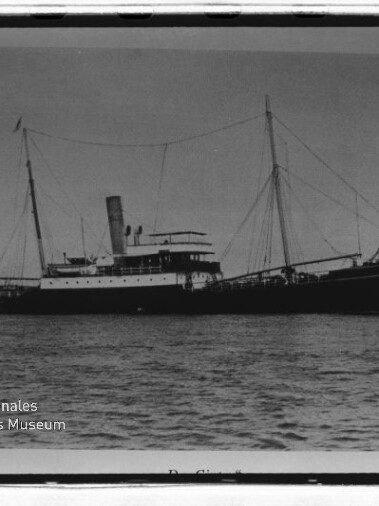 Historisches Schwarzweißfoto eines vorm Anker liegenden Dampfschiffs mit Schornstein und zwei Masten; Museumsstempel links unten.
