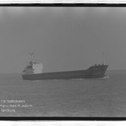 Frachtschiff in Seitenansicht auf ruhiger See mit leichter Heckwelle; Wasserzeichen 