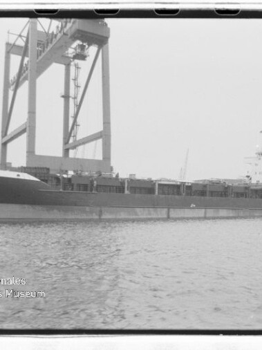 Frachtschiff CITA an einem Kai unter einem großen Hafenportalkran, ruhiges Wasser im Vordergrund.