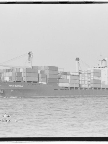Containerschiff City of Amsterdam mit aufgestapelten Ladungskontainern und zwei Ladekränen auf ruhiger See.