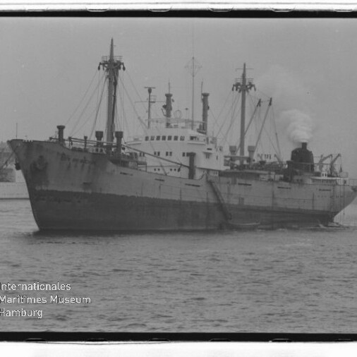 Großes Frachtschiff mit Masten und rauchendem Schornstein im Hafen; Wasserzeichen des Internationalen Maritimen Museums Hamburg