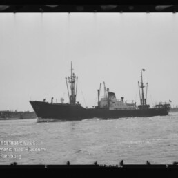 Frachtschiff mit Masten und Aufbauten fährt auf ruhigem Wasser; links unten Wasserzeichen Internationales Maritimes Museum Hamburg.