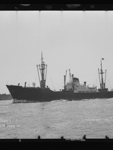 Frachtschiff mit Masten und Aufbauten fährt auf ruhigem Wasser; links unten Wasserzeichen Internationales Maritimes Museum Hamburg.