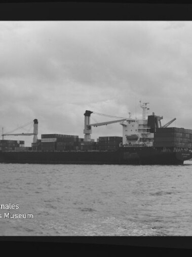 Containerschiff mit gestapelten Containern und Kränen auf ruhiger See, bewölkter Himmel; Museumslogo unten links.