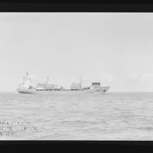 Frachtschiff mit Containern auf ruhiger See in Seitenansicht, Schwarzweißaufnahme mit Museumswasserzeichen unten links.