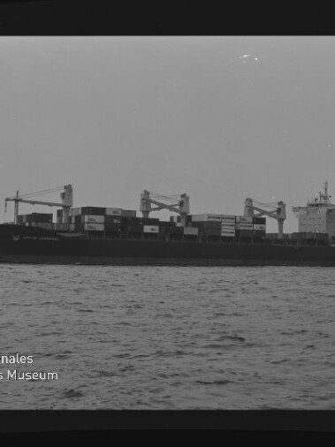 Containerschiff mit gestapelten Containern und Kränen auf ruhiger See; Schriftzug 'Internationales Maritimes Museum Hamburg'