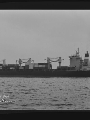 Containerschiff seitlich auf ruhiger See mit Deckskränen, schwarzweißes Foto mit Schriftzug Internationales Maritimes Museum Hamburg