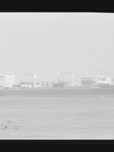 Frachtschiff mit Ladekränen seitlich auf ruhiger See, sichtbarer Negativ-Filmrand und Wasserzeichen des Maritimen Museums Hamburg.