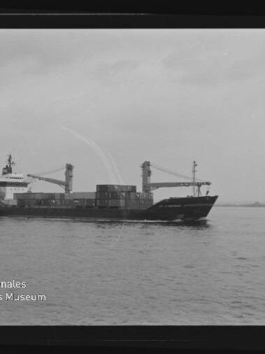 Containerschiff mit zwei Ladekränen und gestapelten Containern fährt auf ruhigem Wasser; Museumslogo links unten.